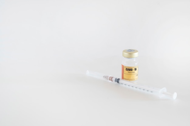 Glazen injectieflacon voor intramusculaire injectie met het vaccin voor covid19 met spuit en naald op witte achtergrond