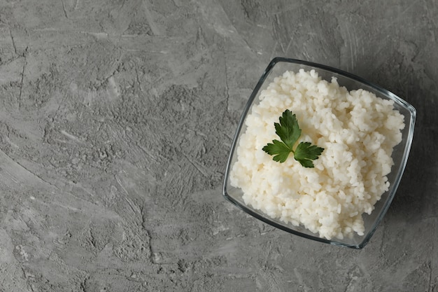 Glazen kom met gekookte rijst op grijze ondergrond