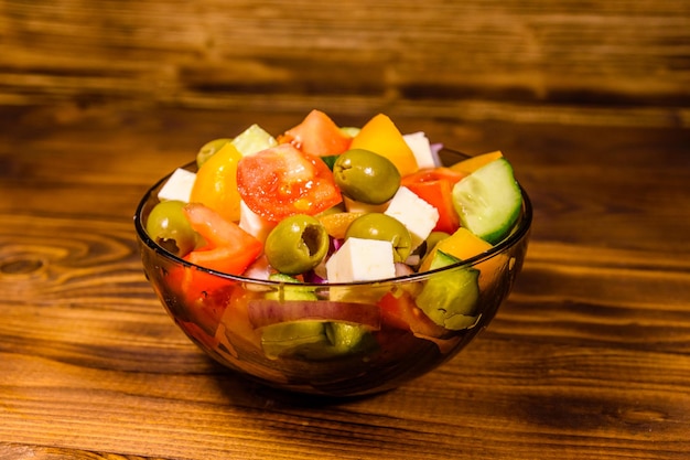 Glazen kom met Griekse salade op houten tafel