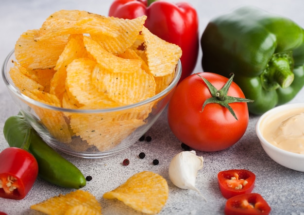 Glazen kom plaat met chips chips met paprika en chili peper op licht