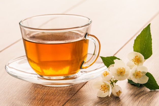 Glazen kopje groene thee met witte jasmijn bloemen op houten achtergrond