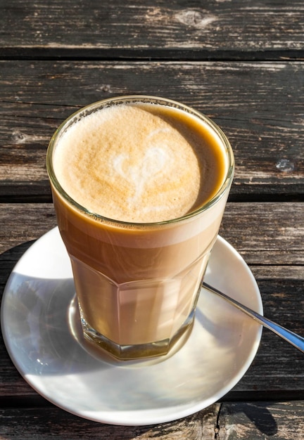 Glazen kopje koffie latte met mooie hartvormige houten tafel