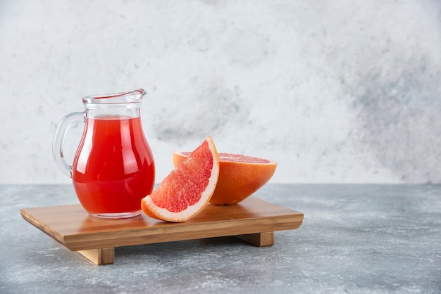 Glazen kruik vers grapefruitsap met plakjes fruit.