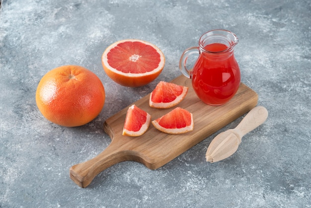 Glazen kruik vers grapefruitsap met plakjes fruit.