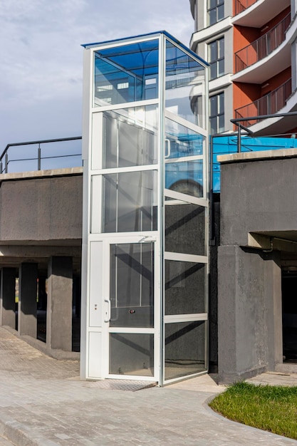 Glazen lift voor gehandicapten en gehandicapten bij de ingang van een modern gebouw. Zorgen voor mensen.