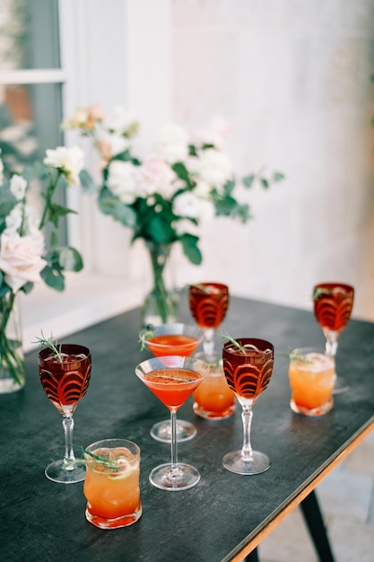 Foto glazen met alcoholische dranken staan op de tafel naast boeketten bloemen