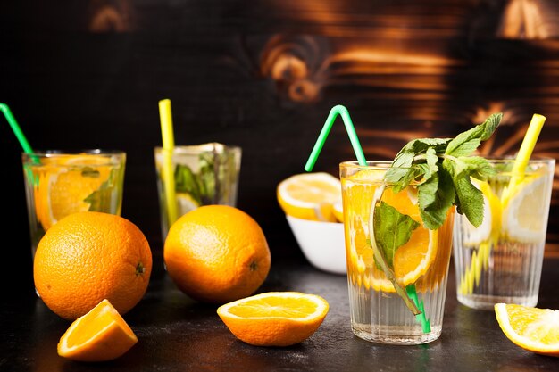 Glazen met orangeade en limonade op donkere vintage houten achtergrond