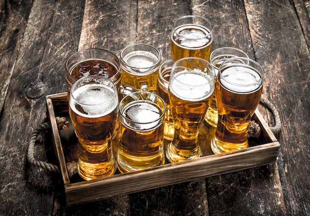 Glazen met vers bier op een oud dienblad. Op een houten tafel.