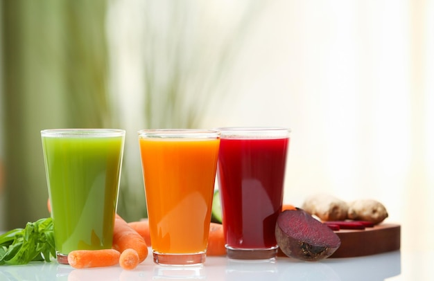 Glazen met verschillende verse sappen en ingrediënten op tafel