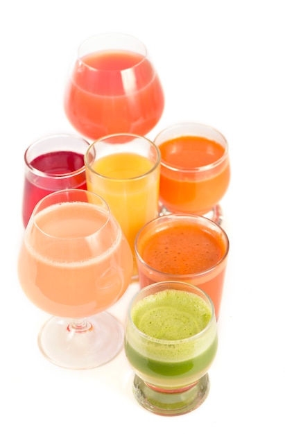 Glazen met verse biologische groente- en vruchtensappen op wit wordt geïsoleerd.