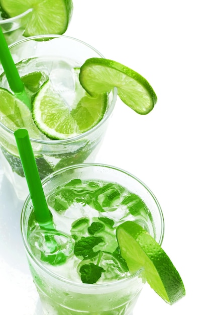 Glazen Mojito highball cocktail of verfrissend drankje met limoen en munt op witte achtergrond