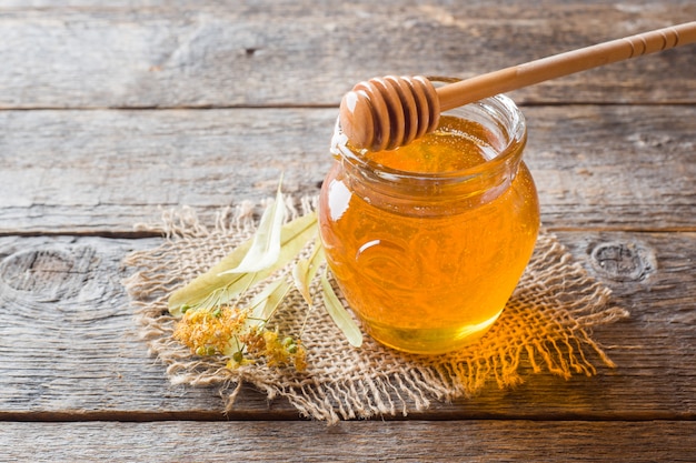 Glazen pot honing, lindebloemen op houten oppervlak