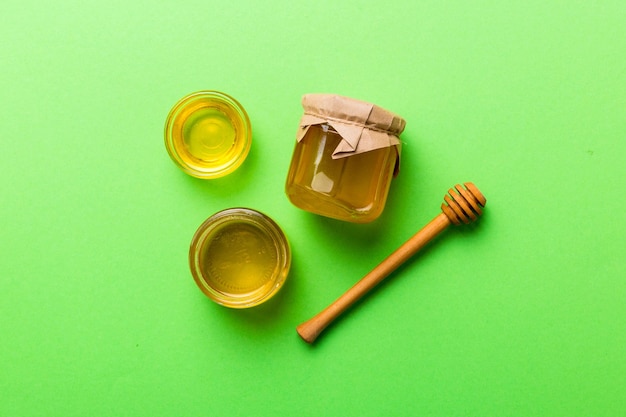 Glazen pot honing met houten drizzler op gekleurde achtergrond Honingpot en dipper hoog boven Bovenaanzicht kopieerruimte