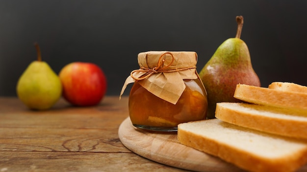 Glazen pot huisgemaakte peer en appeljam met vers fruit op tafel