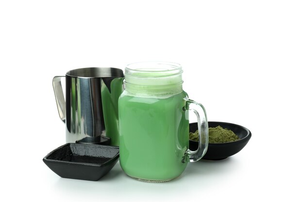 Glazen pot matcha latte en accessoires voor het maken van geïsoleerd op een witte achtergrond