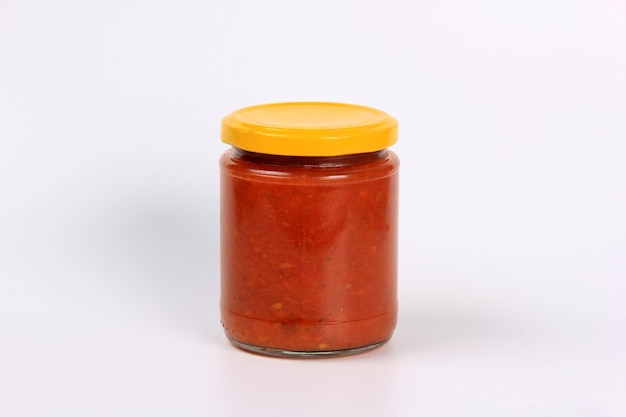 glazen pot met gekookte rode tomatensaus op een witte achtergrond