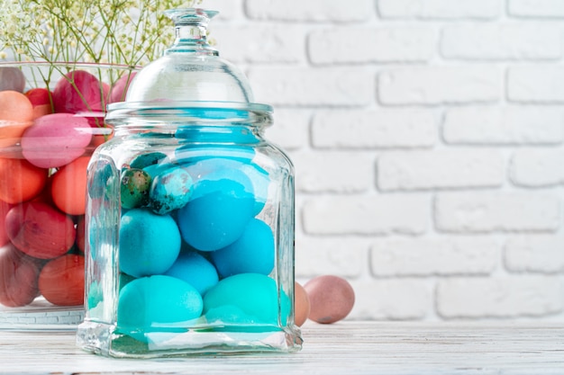 Glazen pot met helder gekleurde eieren voor Pasen viering