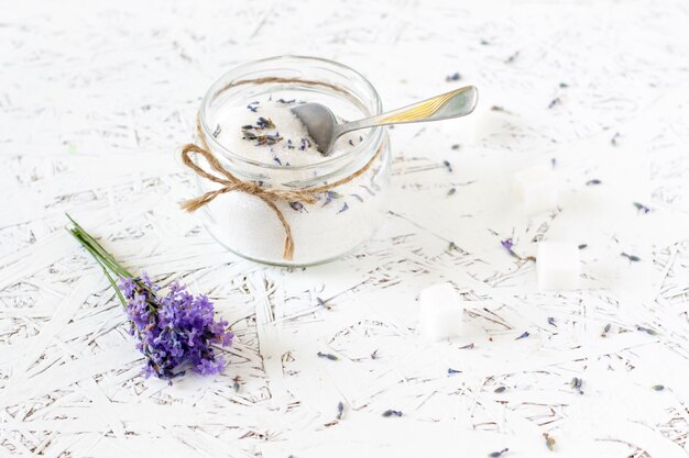 Glazen pot met lavendel suiker, verse lavendel op een lichte houten achtergrond