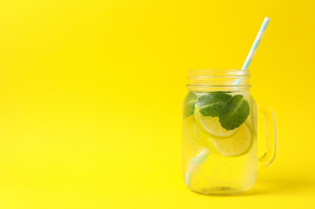 Glazen pot met limonade op gele ondergrond. Vers drankje