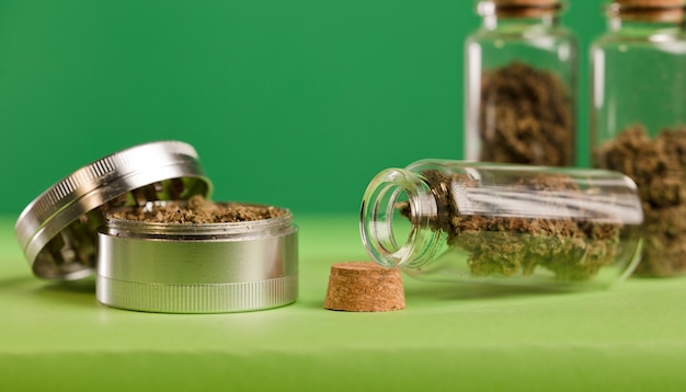 glazen pot met marihuana en grinder groene achtergrond