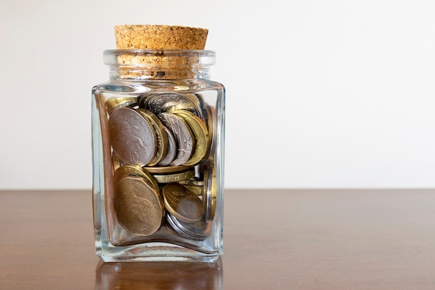 Glazen pot met meerdere munten en kurken deksel. Economie en financiën concept.