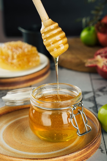 Glazen pot met verse honing, honinglepel, appel en granaatappel. Concept Joods Nieuwjaar Prettige vakantie Rosj Hasjana. lay-out van traditionele symbolen. Uitzicht van boven. Shana Tova