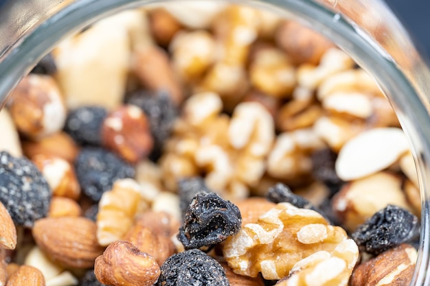 Glazen pot vol met diverse noten met amandelen, hazelnoten, cashewnoten en rozijnen in een macrofoto