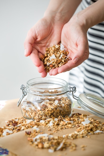 Glazen pot zelfgemaakte biologische granola met kokos en pecannoten op de achtergrond van bakpapier