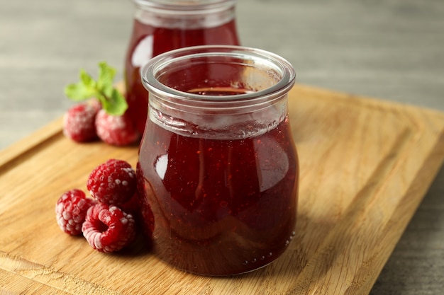 Glazen potten frambozenjam met ingrediënten op een houten bord