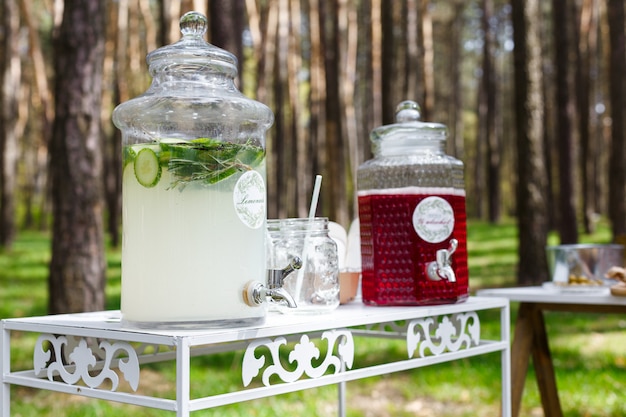 Glazen potten met verse limonade en snacks op houten tafels