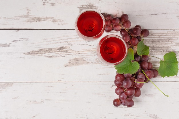 Glazen rode wijn en rode druif op witte houten bovenaanzicht als achtergrond