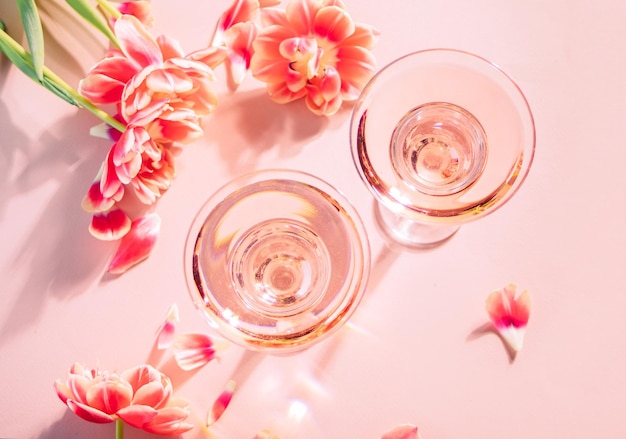 Glazen roze cocktail met bloemen en bloemblaadjes Verjaardagsfeestje of Valentijnsdag romantisch date paar concept Bovenaanzicht