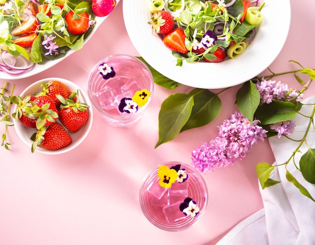 Glazen roze violet paarse cocktail versierde bloemen altviool viooltjes verse vitaminesalade met eetbare bloemen en verse aardbeien