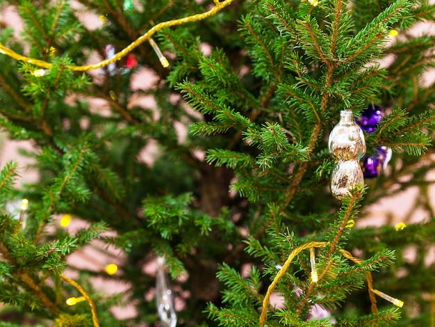 Glazen speelgoed en slingerverlichting op kerstboom