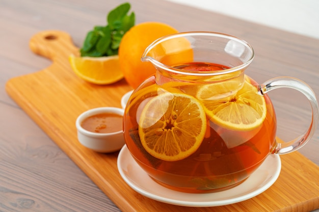Glazen theepot met zwarte thee en stukjes citrus