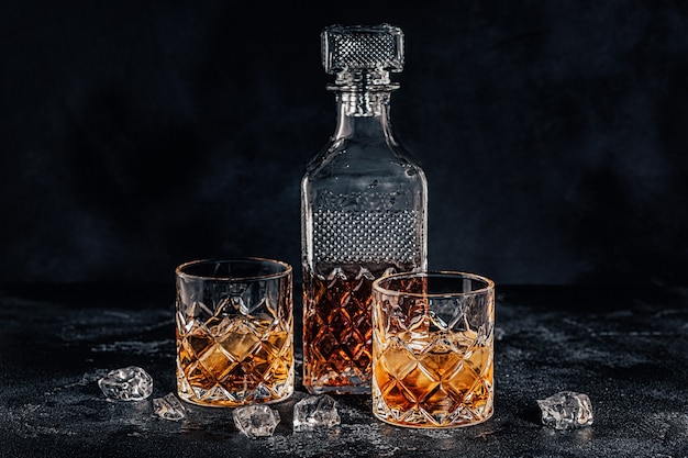 Glazen van de whisky met een vierkante karaf op een zwarte stenen achtergrond.