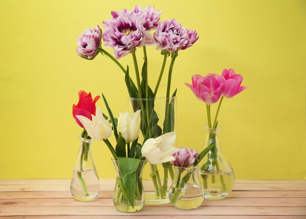 Glazen vazen met prachtige tulpen op kleur achtergrond