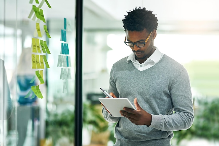 Foto glazen wand zakelijke tablet en zwarte man die onderzoek en strategie plant op kantoorwerkplek technologiebord en afrikaanse mannelijke professional met plaknotities voor online planning en brainstormen