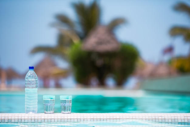 Glazen wateren en flessen achtergrond zwembad