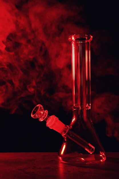 Glazen waterpijp en rook op zwarte achtergrond afgezwakt in rood Rookapparaat