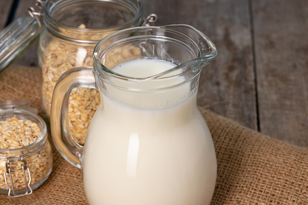 Glazen werper melk en havervlokken op houten tafel