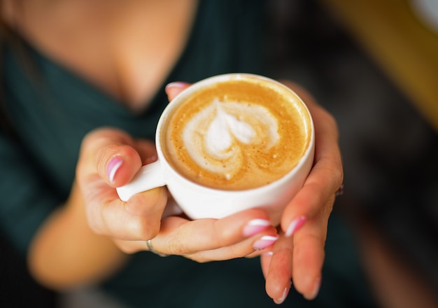 GLB van koffie, cappuccino, latte in vrouwenhanden close-up