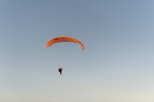 Glijscherm dat over de kust bij zonsondergang vliegt. Paragliding sport