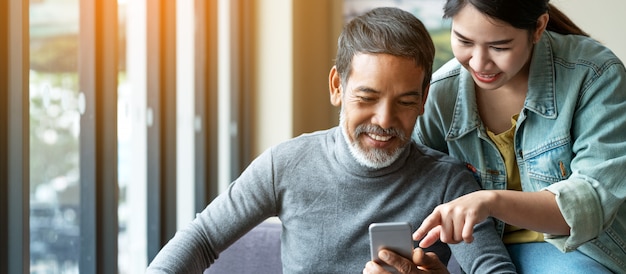 Glimlach aantrekkelijke stijlvolle korte baard volwassen Aziatische man met smartphone met jonge vrouw.