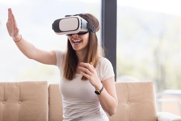 Glimlach gelukkige vrouw die ervaring opdoet met het gebruik van VR-headset-brillen van virtual reality thuis