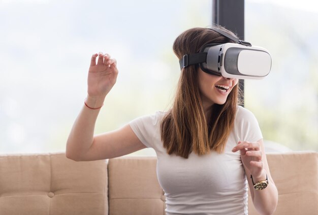 Glimlach gelukkige vrouw die ervaring opdoet met het gebruik van VR-headset-brillen van virtual reality thuis