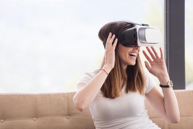 Glimlach gelukkige vrouw die ervaring opdoet met het gebruik van VR-headset-brillen van virtual reality thuis