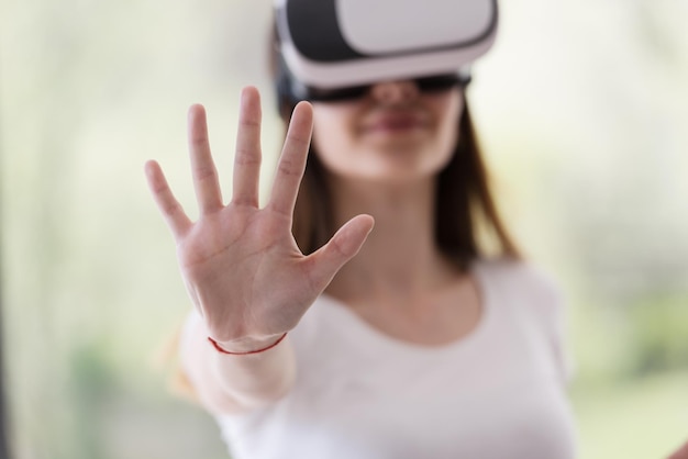 Foto glimlach gelukkige vrouw die ervaring opdoet met het gebruik van vr-headset-brillen van virtual reality thuis