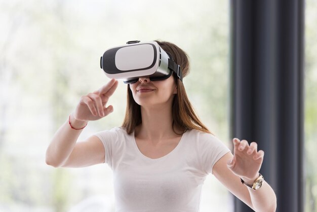 Glimlach gelukkige vrouw die ervaring opdoet met het gebruik van VR-headset-brillen van virtual reality thuis