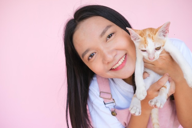 Glimlach jong meisje met kat op roze achtergrond